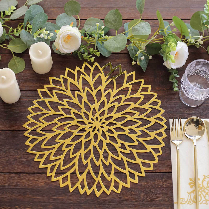 Gold floral placemat on a wooden table with candles and greenery decorations.