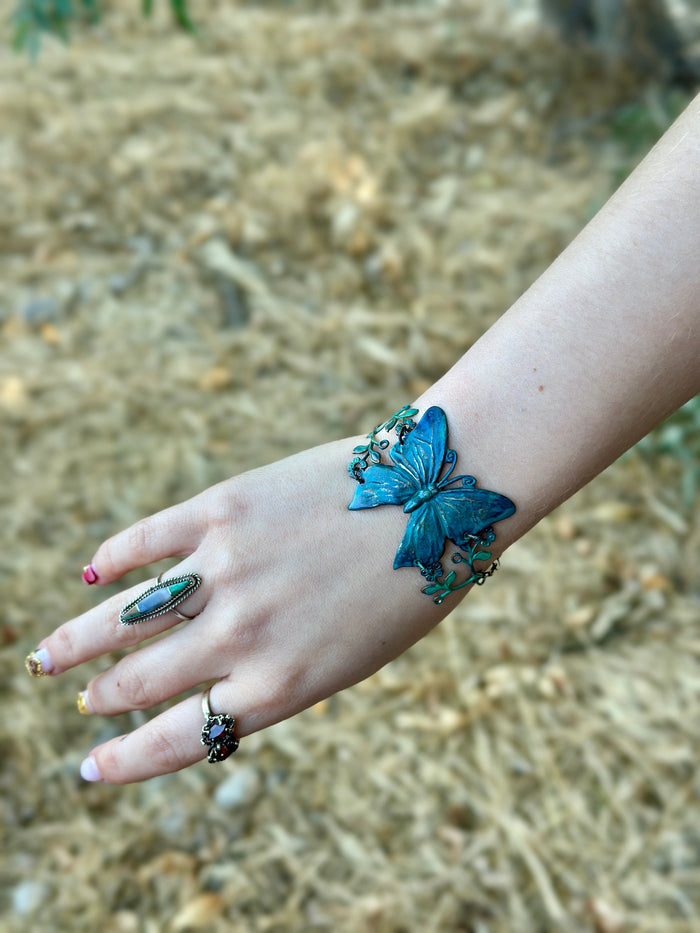 Hand with butterfly bracelet and rings.