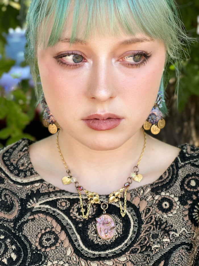 Woman with blue hair and ornate necklace
