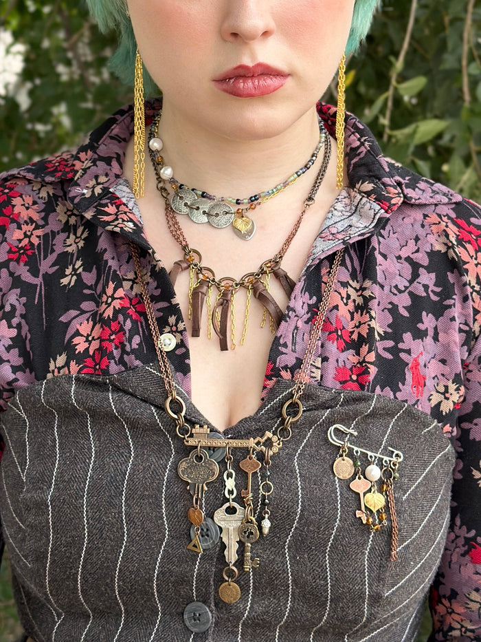 Woman wearing key jewelry and floral shirt.