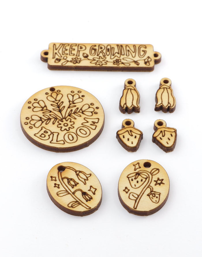 Wooden charms with Keep Growing and floral designs.