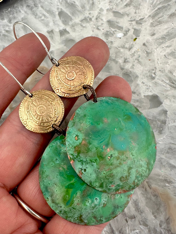 Hand holding green and gold disc earrings