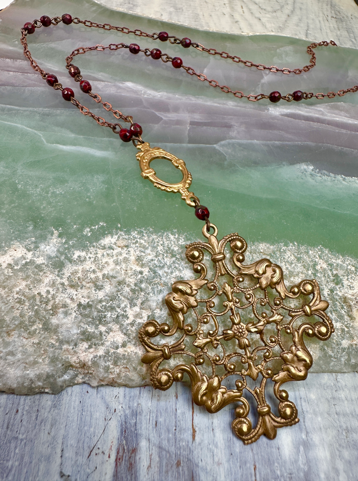 Ornate gold pendant necklace with red beads