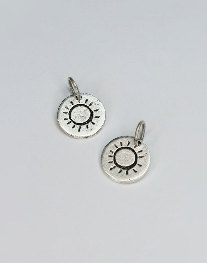 Two silver sun charm pendants