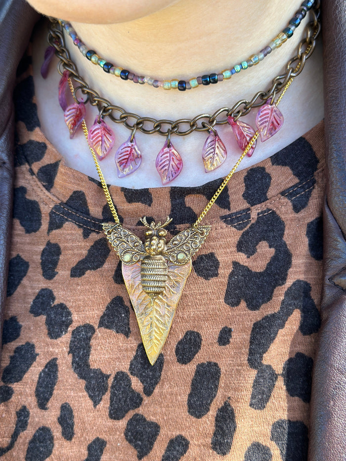 Bee pendant necklace and layered beaded necklaces on leopard print.