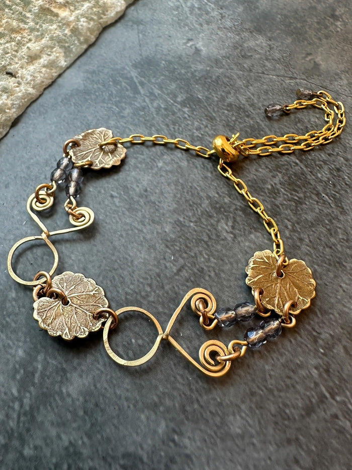 Gold bracelet with leaf charms and beads.